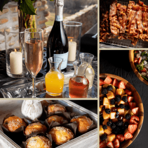 Champagne, juices, candles, bacon, pastries, and a fruit salad are arranged for a Sunday brunch at Ancient Lore Village on a dark table.